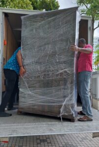 Two Citywide employee providing furniture moving service by carrying a large almirah inside the truck