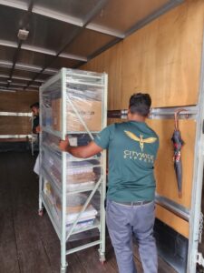 Two Citywide Express Employee moving a wrapped trolley filled with office material into the lorry