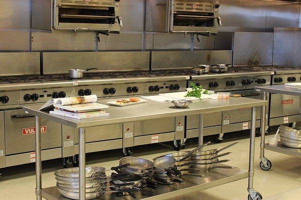 A commercial kitchen setup featuring large gas appliances and utensils