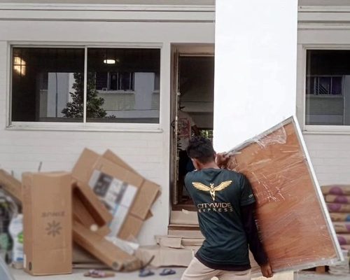 A Citywide employee providing residential moving service by carrying a large wooden frame